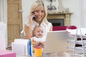 Mother and baby in home office with laptop and telephone