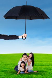 Family playing at field and protected by umbrella